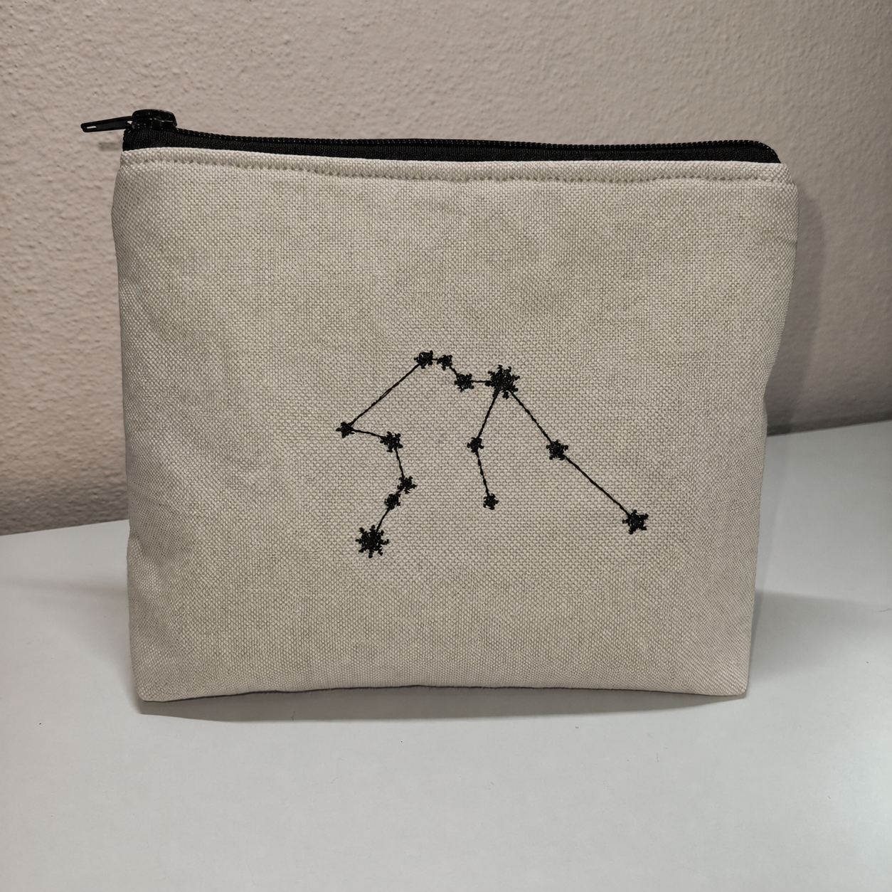 Necessaire bege com bordado preto de constelação e fecho preto