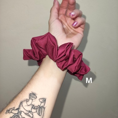 Mão com unhas rosa cintilante e elástico de tecido rosa granada