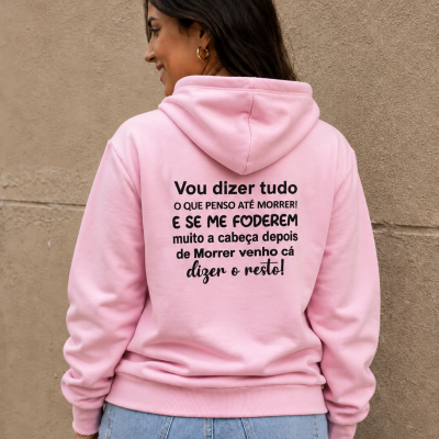 Mulher de costas a usar sweatshirt rosa com texto preto nas costas, contra parede bege texturizada