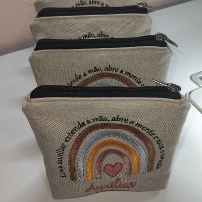 Conjunto de bolsas em tecido bege com fecho e bordados coloridos e texto em português