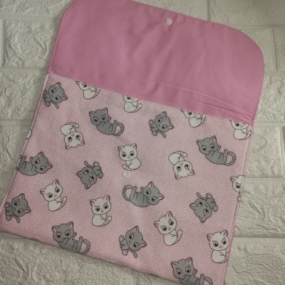Capa rosa com padrão de gatos cinzentos e brancos em tecido sobre parede branca texturada