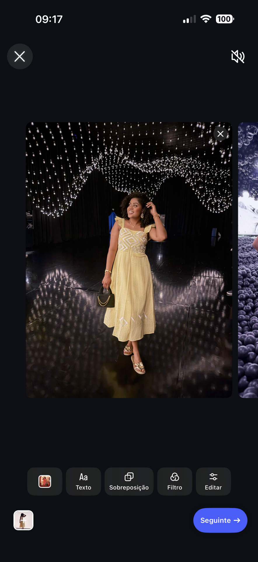 Mulher com vestido amarelo e mala preta sob muitas luzes penduradas