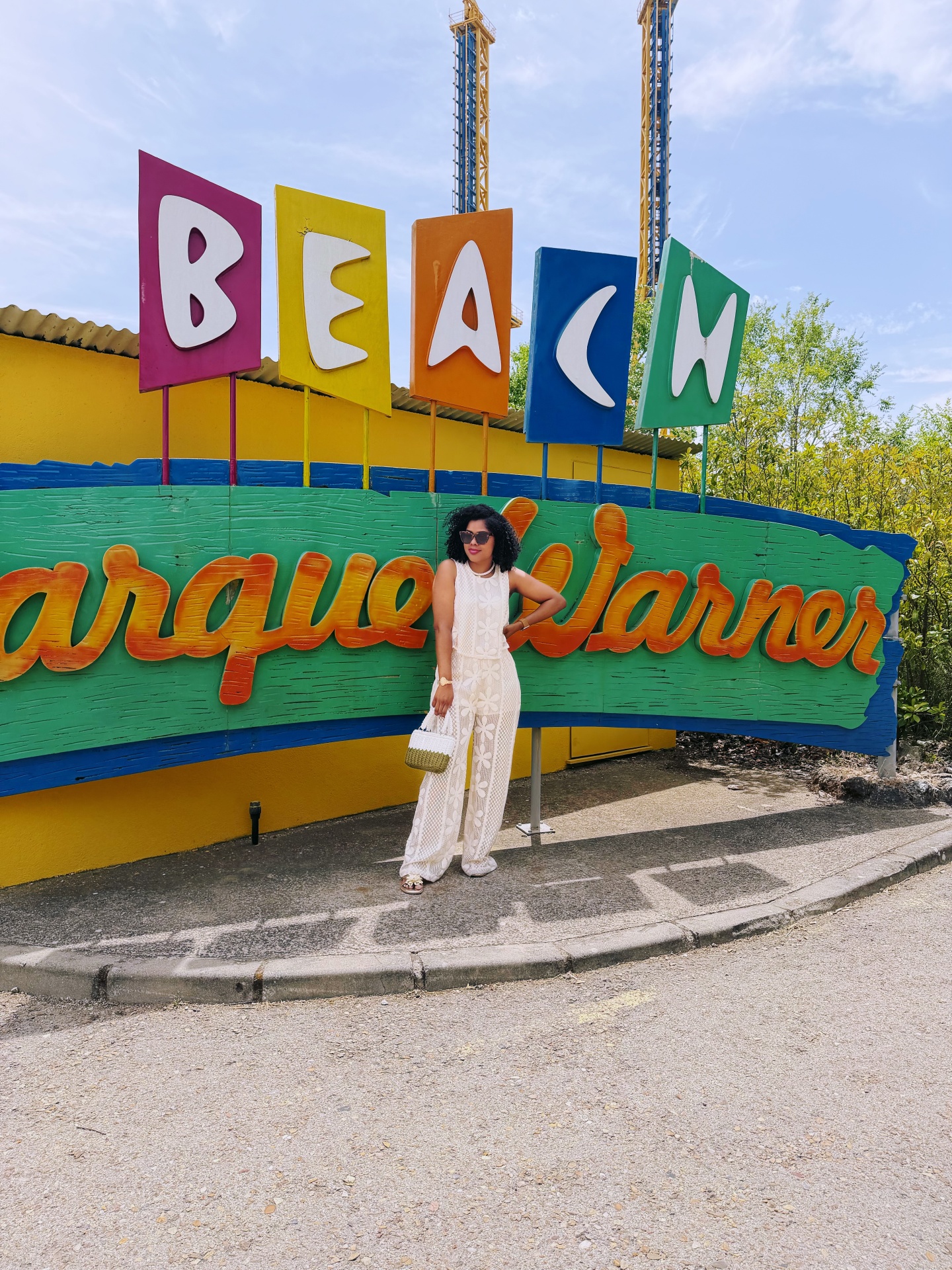 Placa colorida Parque Warner com mulher vestidos branco e óculos
