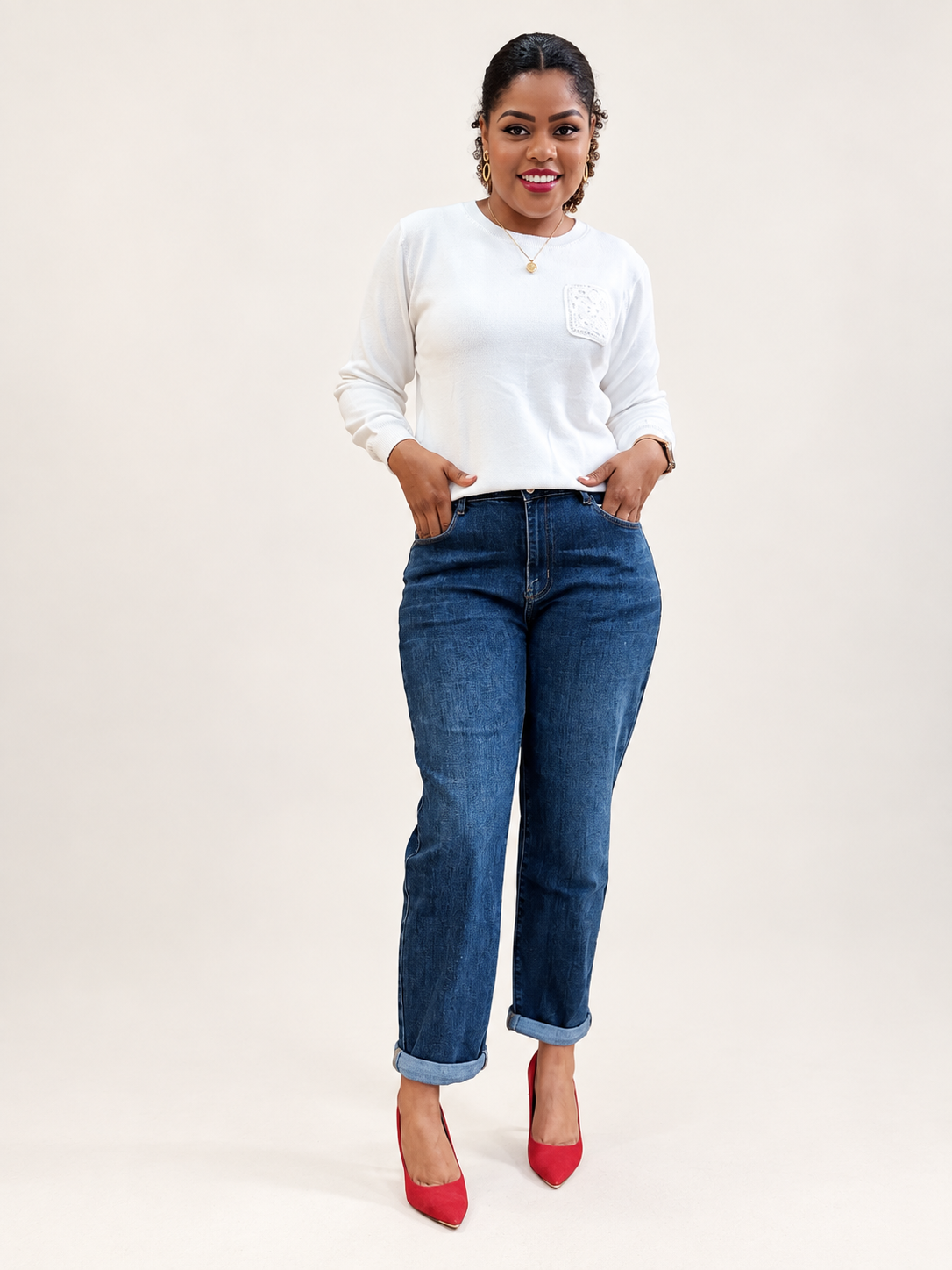 Mulher com camisola branca, jeans azuis e sapatos vermelhos, em fundo neutro.