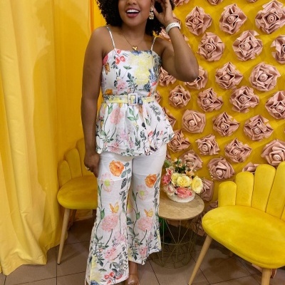 Mulher com conjunto feminino floral em cenário com decoração amarela e flores