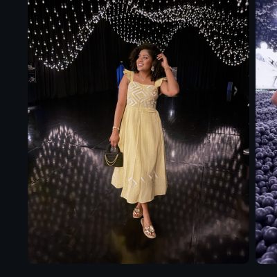 Mulher com vestido amarelo e mala preta sob muitas luzes penduradas