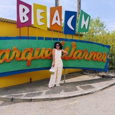 Placa colorida Parque Warner com mulher vestidos branco e óculos
