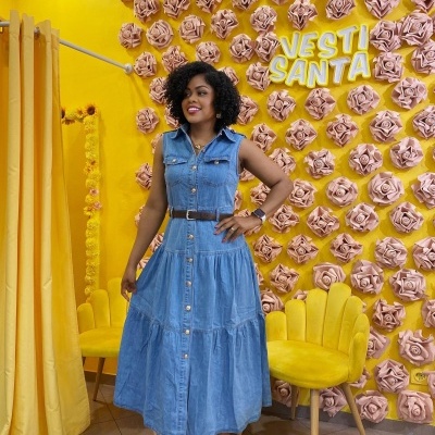 Vestido midi de ganga azul com botões e cinto castanho, parede amarela com flores rosas 3D, cadeiras amarelas