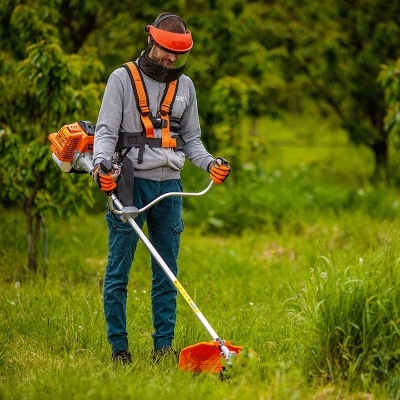 Pessoa a usar corta-relva com motor laranja em ambiente verde