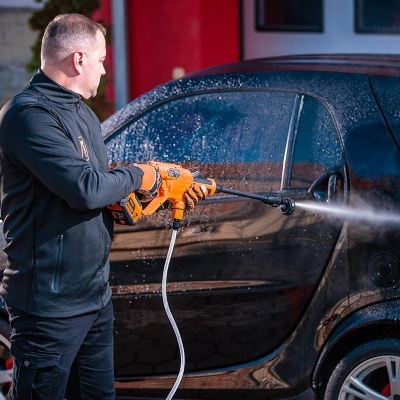 Homem a lavar carro pequeno preto com lava-jato portátil laranja