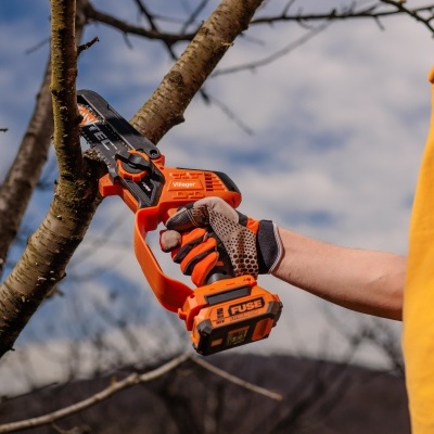 Serra elétrica portátil laranja e preta Villager cortando ramo de árvore ao ar livre