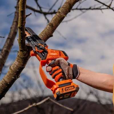 Motosserra elétrica portátil laranja e preta cortando galho de árvore