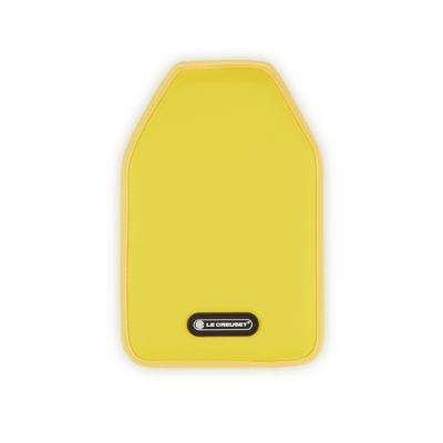 Tábua de corte amarela com bordas castanhas e etiqueta Le Creuset