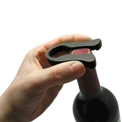 Mão segurando abridor de garrafas preto numa garrafa de vinho com cápsula vermelha
