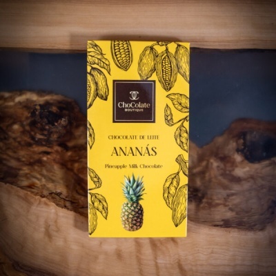 Embalagem amarela de chocolate de leite com ananás sobre superfície de madeira