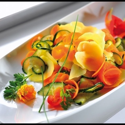 Prato branco com salada de tiras de legumes e flores comestíveis coloridas