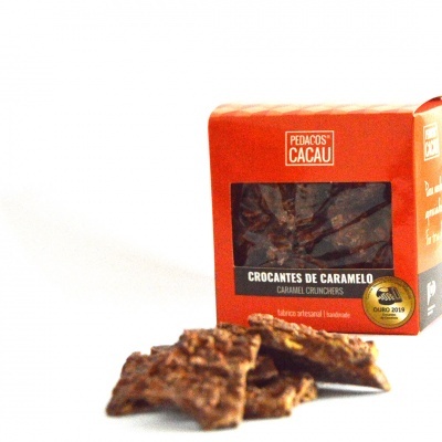 Pacote vermelho de crocantes de caramelo Pedaços de Cacau com pedaços do produto na frente