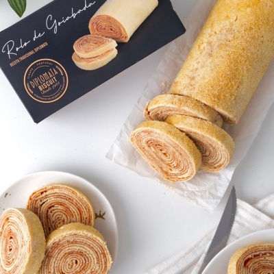 Rolo de Guimbara em pedaços junto à embalagem preta em superfície branca