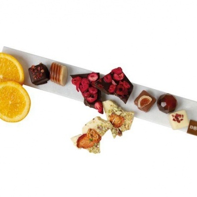 Variedade de chocolates artesanais com frutas e frutos secos sobre base branca com logótipo BISKA