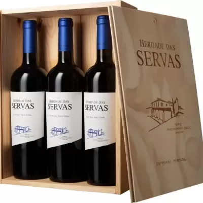 Três garrafas de vinho tinto Herdade das Servas numa caixa de madeira clara