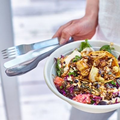 Salada colorida com batatas fritas em prato branco e talheres