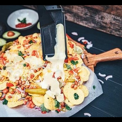 Nachos com queijo derretido e vários ingredientes em superfície escura