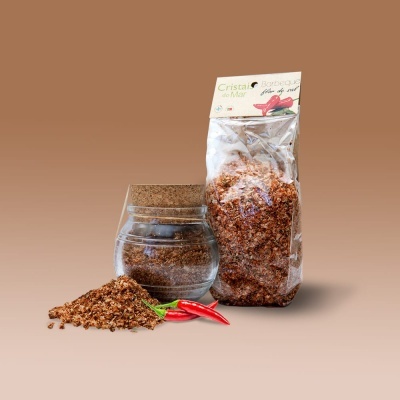 Frasco de vidro com tampa de cortiça e saco plástico com tempero castanho, malaguetas vermelhas e tempero espalhado.