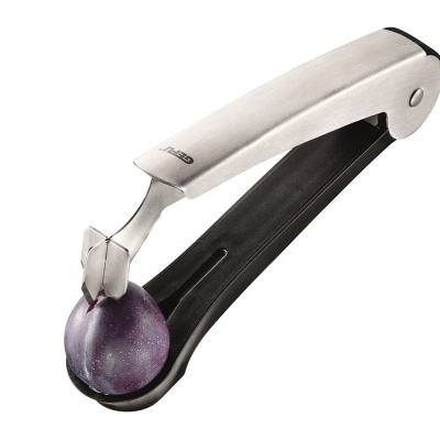 Espremedor de azeitonas prateado com plástico preto a espremer uma azeitona roxa.