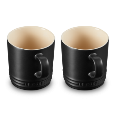 Duas canecas de cerâmica pretas com interior creme e texto LE CREUSET em relevo.