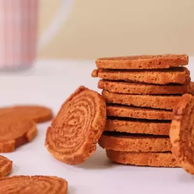 Bolachas redondas castanhas com padrão circular empilhadas com caneca listrada ao fundo