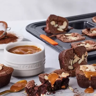 Muffins de chocolate com amêndoas e caramelo com taça branca de caramelo ao lado