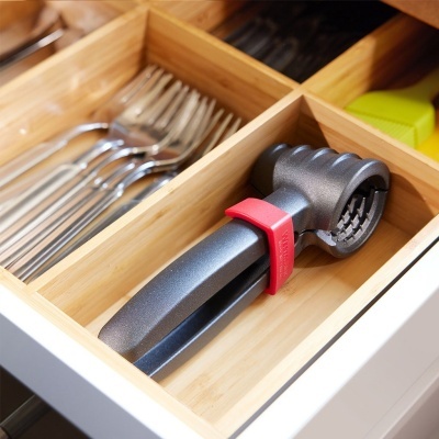 Garrafa metálica cinzenta com pega preta e correia vermelha numa gaveta organizada