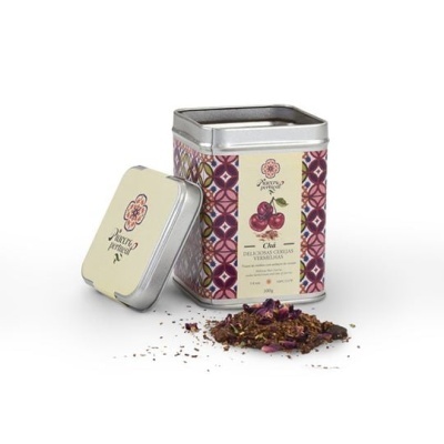 Caixa metálica decorada com chá solto à frente