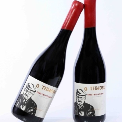 Duas garrafas de vinho tinto O TEIMOSO com rótulos brancos e cápsulas vermelhas