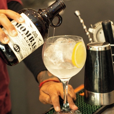Garrafa MOMBASA a verter líquido num copo de cocktail com gelo e limão num bar