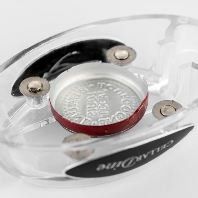 Produto oval transparente com botão de bateria prateado e etiqueta preta BLANQline