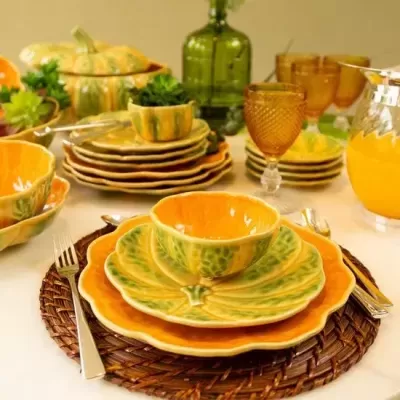 Conjunto de loiça em cerâmica com padrão de folhas, copos âmbar e jarra de vidro em mesa posta.