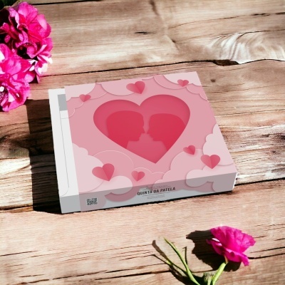 caixa rosa decorada com corações numa mesa de madeira com flores cor-de-rosa ao redor