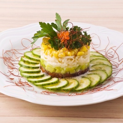 Torta colorida em prato branco com fatias de pepino e ervas frescas