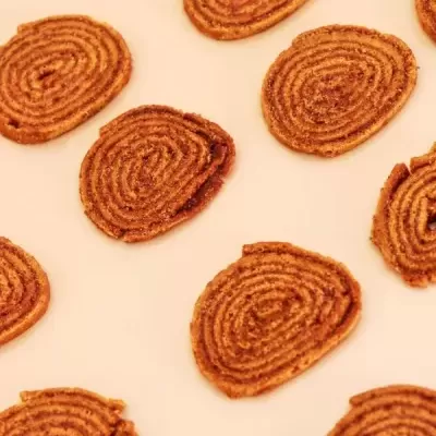 Snack crocante redondo castanho com padrão em espiral sobre fundo claro