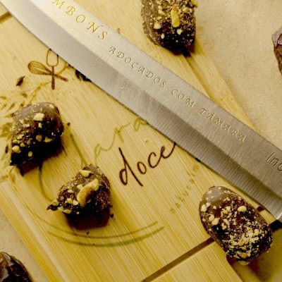 Bombons de chocolate com pedaços de nozes e faca com texto sobre tábua de madeira