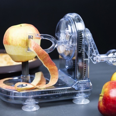 Descascador e fatiador de maçãs transparente usado numa superfície cinzenta