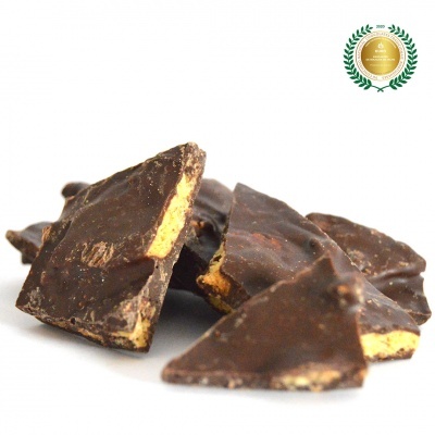 Pedaços irregulares de chocolate negro com recheio amarelo sobre fundo branco com selo dourado