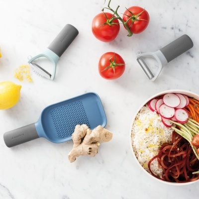 Utensílios de cozinha para ralar e descascar com legumes diversos e tigela de arroz