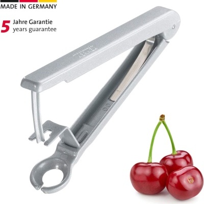 Descascador cinza para cerejas ao lado de três cerejas vermelhas