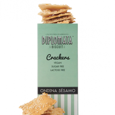 Pacote verde de crackers veganos com sementes de sésamo e crackers empilhados.