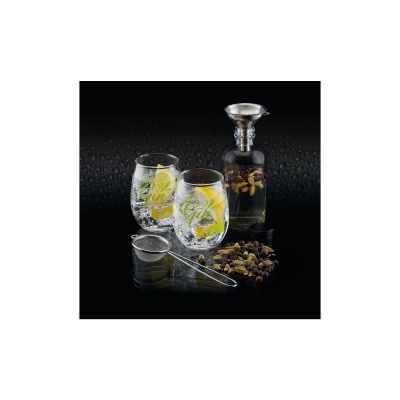 Conjunto de chá com chávenas, infusor, garrafa de vidro e ervas sobre fundo negro molhado