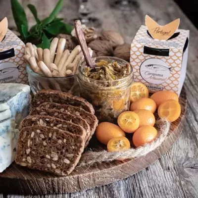 Tábua de madeira com pão, pasta, frutas, queijo e caixas decorativas