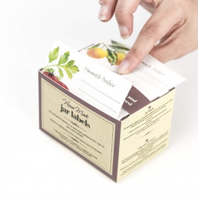 Caixa de etiquetas para plantas Home Made pin labels com ilustrações de frutos, mãos a retirar etiqueta.