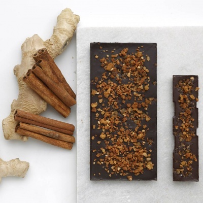 Barra de chocolate escuro com pedaços crocantes, paus de canela e gengibre fresco